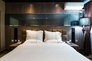 Una habitación de hotel con una cama grande, un teléfono en la mesita de noche y una lámpara.
