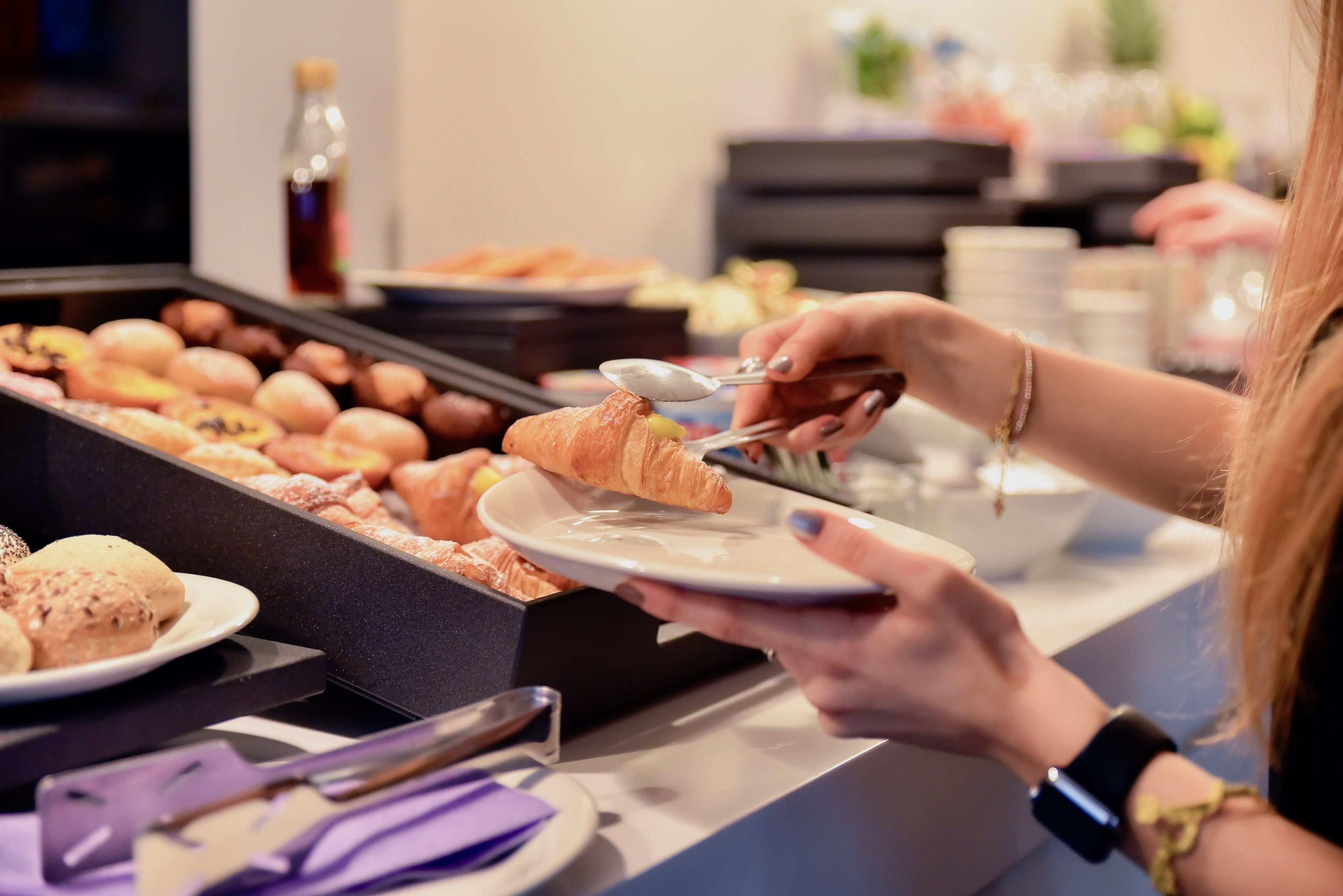 A buffet with various pastries and a bottle of syrup.