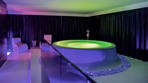 A modern room with a circular light fixture, a small table, and two chairs. - Le Camp Suite & SPA (Padova)