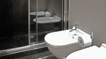 Un baño con lavamanos blanco, inodoro y cabina de ducha de vidrio.