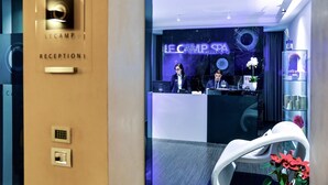 A reception area with a modern design, including a reception desk, a digital sign displaying "LE CAMP SPA", and a reception counter. - Le Camp Suite & SPA (Padova)