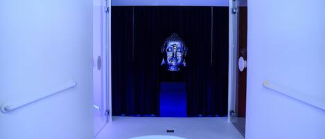 A modern, illuminated hallway with a Buddha statue at the end.