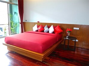 A hotel room with a large bed, wooden headboard, and a small table with a vase of flowers. - Eva villa Rawai 3 bedrooms private pool (Rawai)