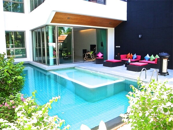 A modern outdoor pool area with a glass-enclosed lounge, red and black seating, and a wooden ceiling. - Eva villa Rawai 3 bedrooms private pool (Rawai)