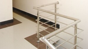 A hallway with a modern chandelier and a metal handrail.