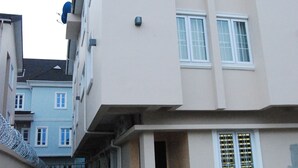 A multi-story building with a central staircase leading to the entrance, a visible air conditioning unit, and a small balcony on the second floor.