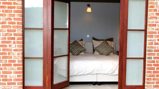 A room with a bed, two pillows, a nightstand, and a wall-mounted light fixture. - B&B Laurus (Ypres)