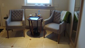 A room with two armchairs, a small table with a laptop, a window with blinds, and a radiator. - B&B Laurus (Ypres)