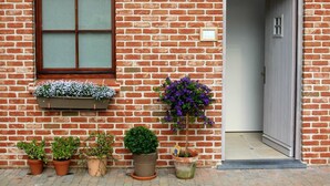 A brick building with a window, a door, and potted plants. - B&B Laurus (Ypres)