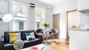 A modern living room with a black leather sofa, two armchairs, a coffee table, and a globe. - One Bed Serviced Apts near Oxford Street (London)