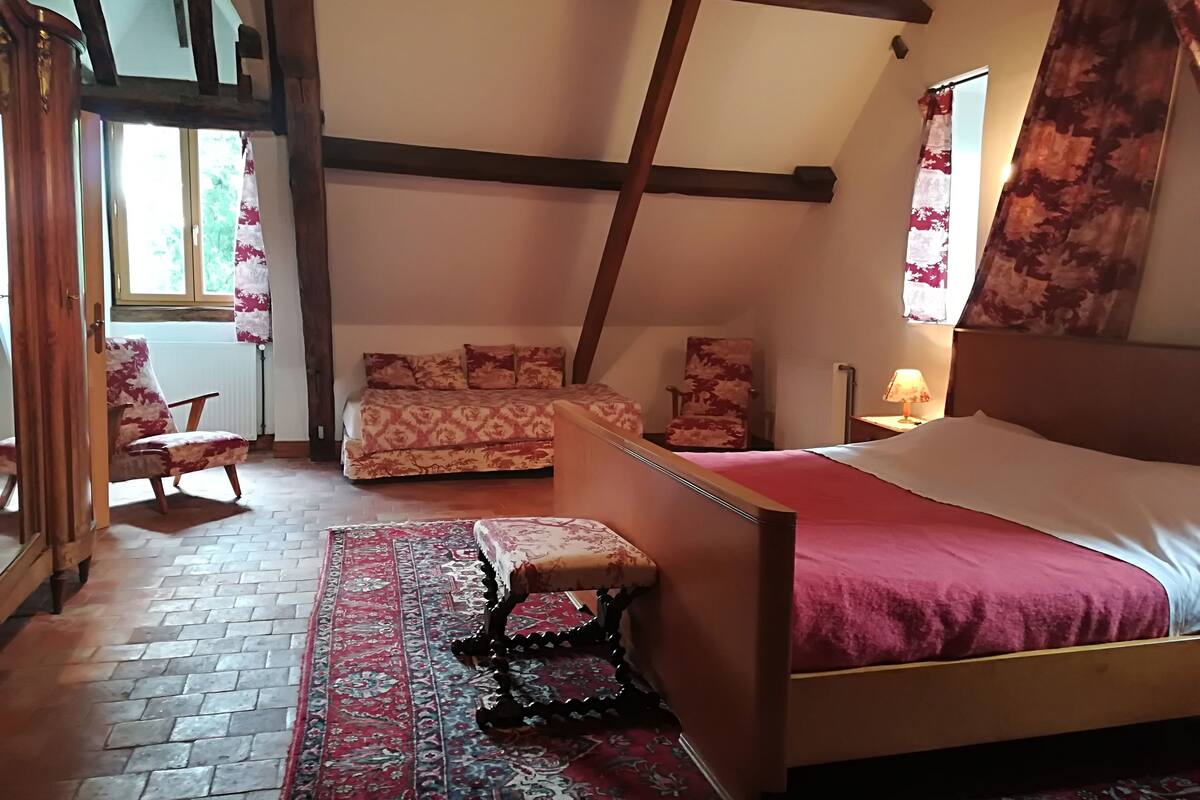 A bedroom with a bed, a chair, a sofa, and a patterned rug.