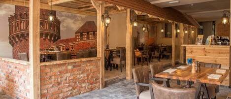 A restaurant with brick walls, wooden beams, and a tiled floor.