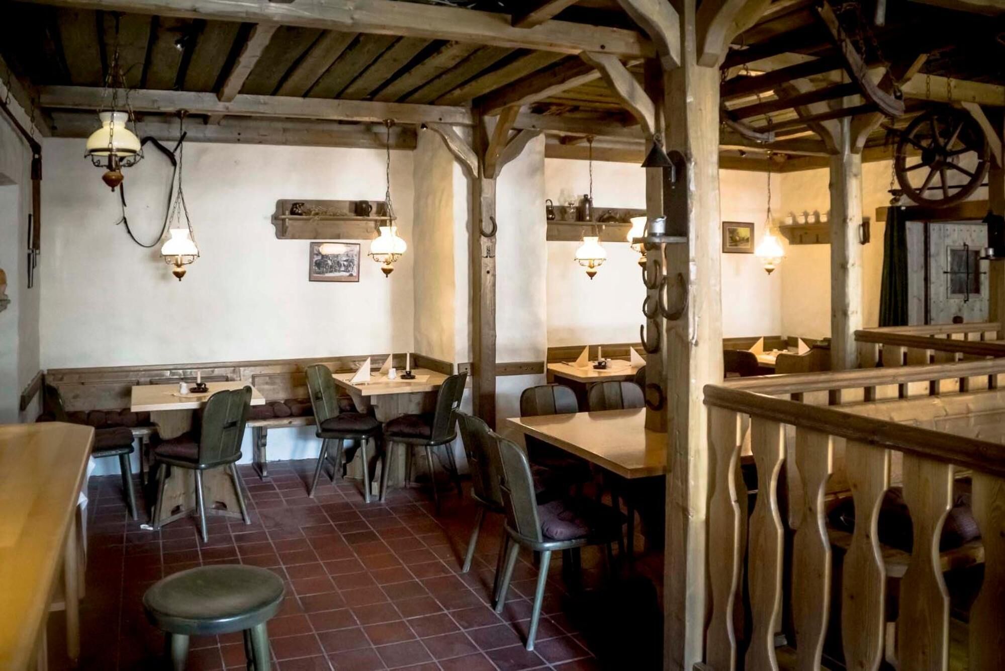 Un comedor rústico con vigas de madera, paredes de ladrillo visto y lámparas colgantes tradicionales.