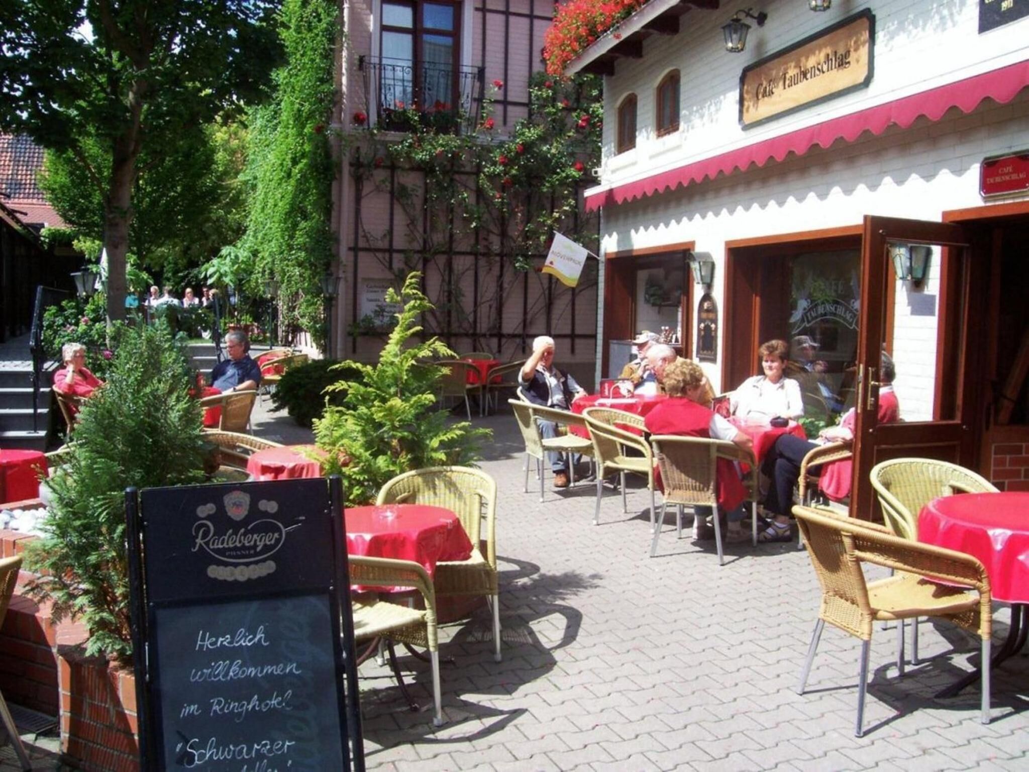 An outdoor cafe with tables and chairs, a signboard, and a small Christmas tree.