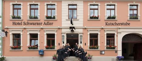Hotel Schwarzer Adler und Kutscherstube mit einer Gruppe von Personen vor der Treppe.