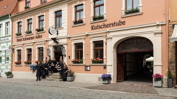 Un hôtel dont la façade porte une enseigne indiquant « Hotel Schwarzer Adler » et « Kutscherstube ».