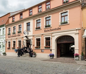 Un hôtel dont la façade porte une enseigne indiquant « Hotel Schwarzer Adler » et « Kutscherstube ».