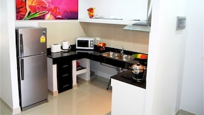Una cocina compacta con refrigerador, microondas y lavamanos.