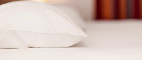 A white pillow on a bed in a hotel room.