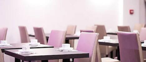 A conference room with tables set for a meeting, equipped with chairs and a whiteboard.