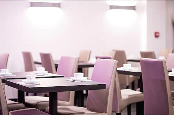 A conference room with tables set for a meeting, equipped with chairs and a whiteboard.