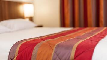 A hotel room with a bed featuring a multicolored striped blanket.