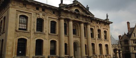 A historic building with classical architecture, featuring large columns and statues on the roof.