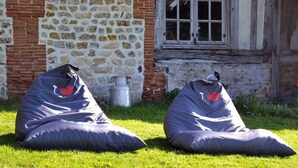 Two bean bags outside a building with a stone wall and a window. - Maison D'hôtes La Bihorée (Saint-Jean-de-Livet)