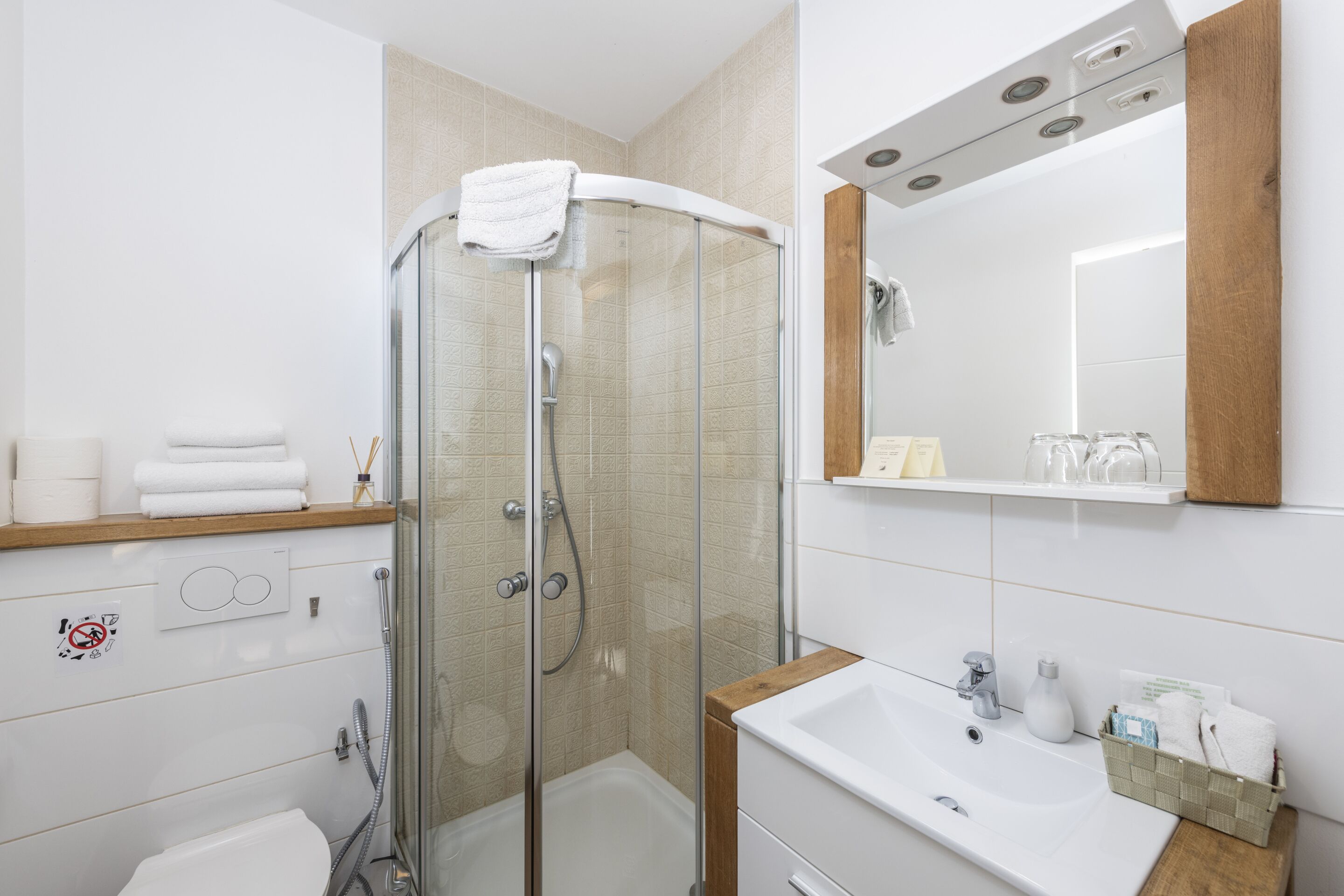 A modern bathroom with a glass-enclosed shower, a white sink, and a wooden vanity.