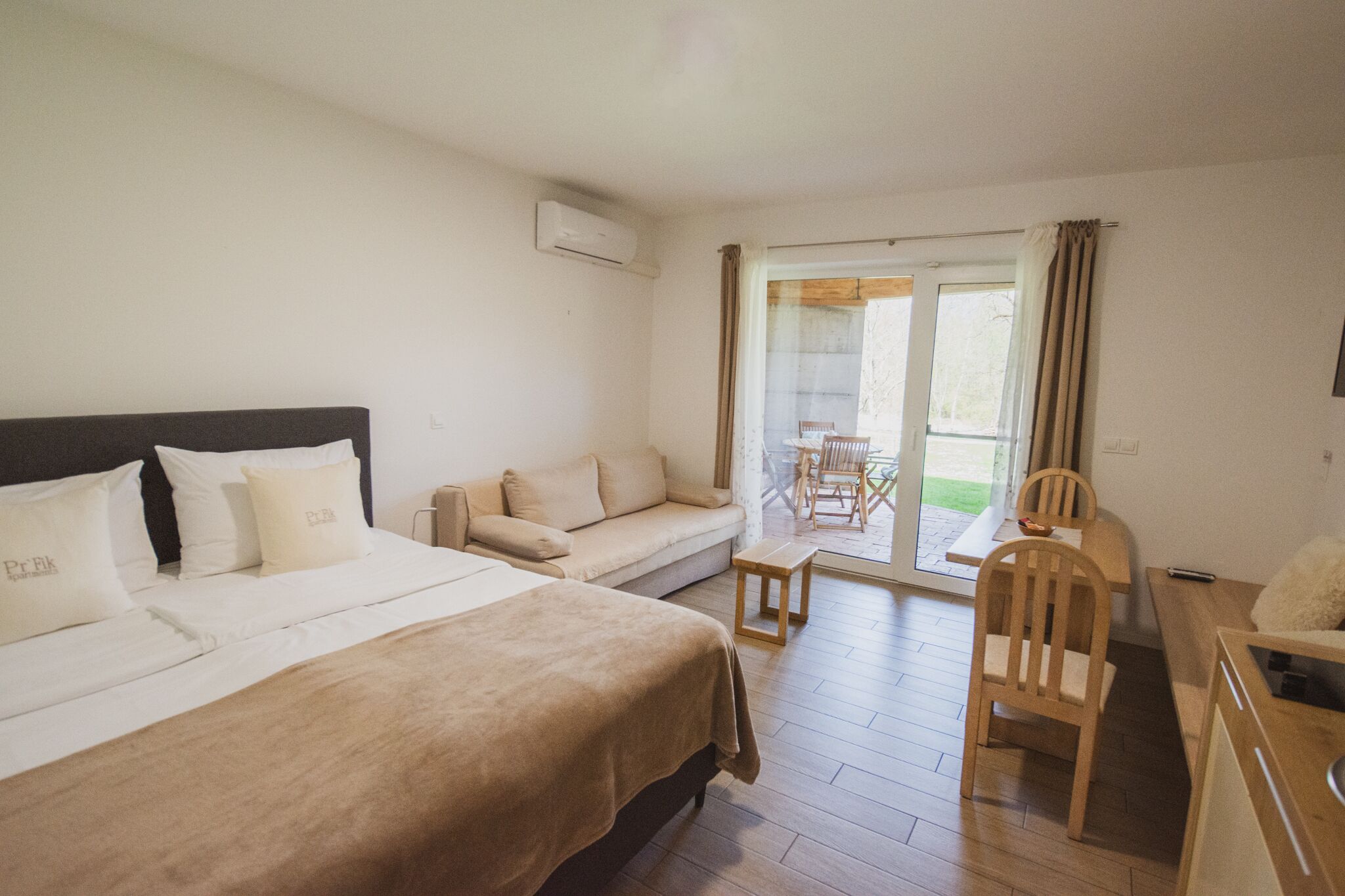 Une chambre d’hôtel avec un lit, un canapé, un bureau et une chaise. Il y a une fenêtre avec des rideaux et une vue sur l’extérieur.