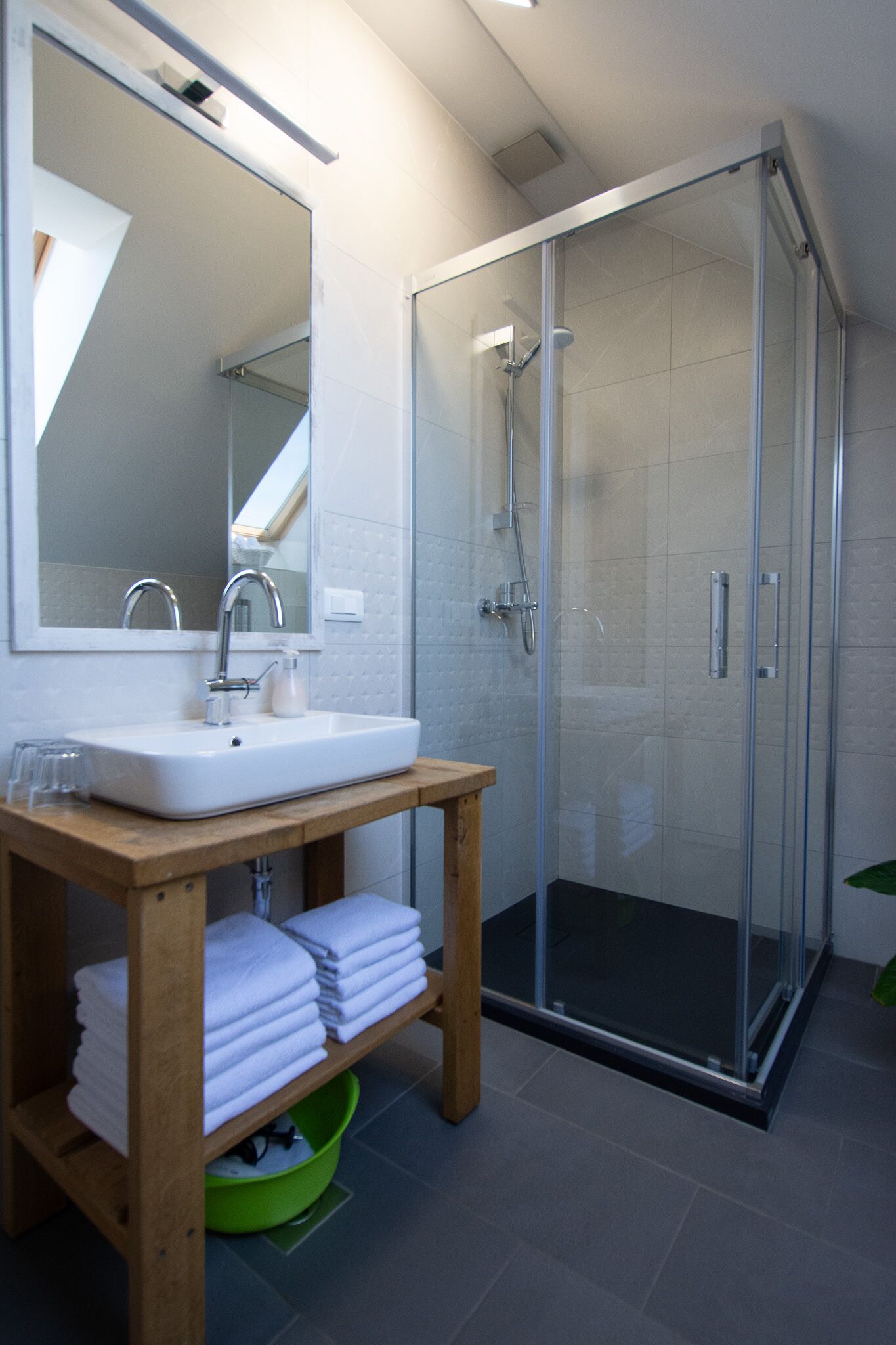 Een moderne badkamer met een douchecabine van glas, een houten wastafelmeubel en een spiegel.