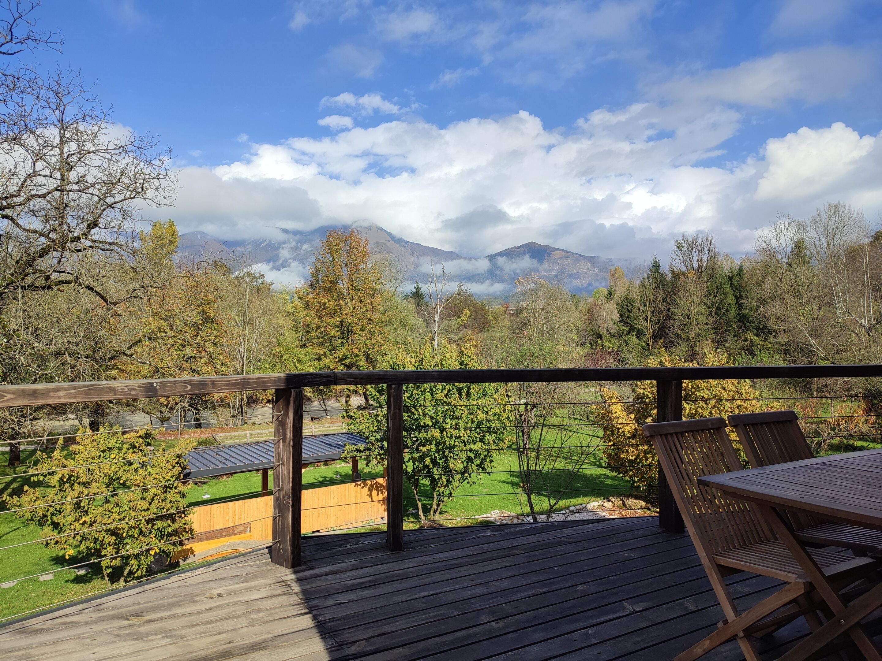 Una terraza de madera con vistas a un paisaje verde y montañas a lo lejos.