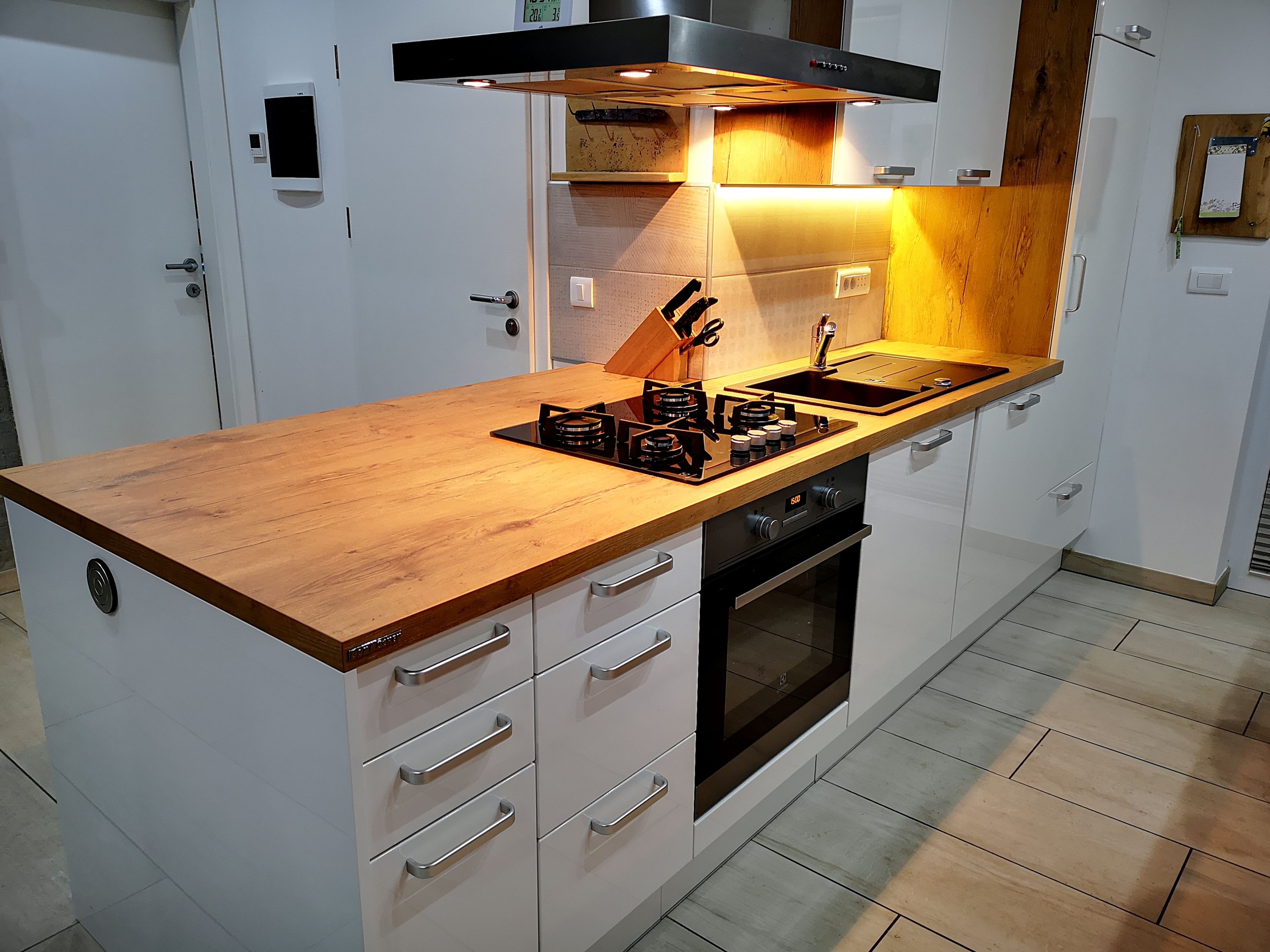 A modern kitchen with a wooden countertop, built-in oven, and stainless steel appliances.