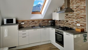 A modern kitchen with white cabinets, a skylight, a microwave, a coffee maker, and a stove.