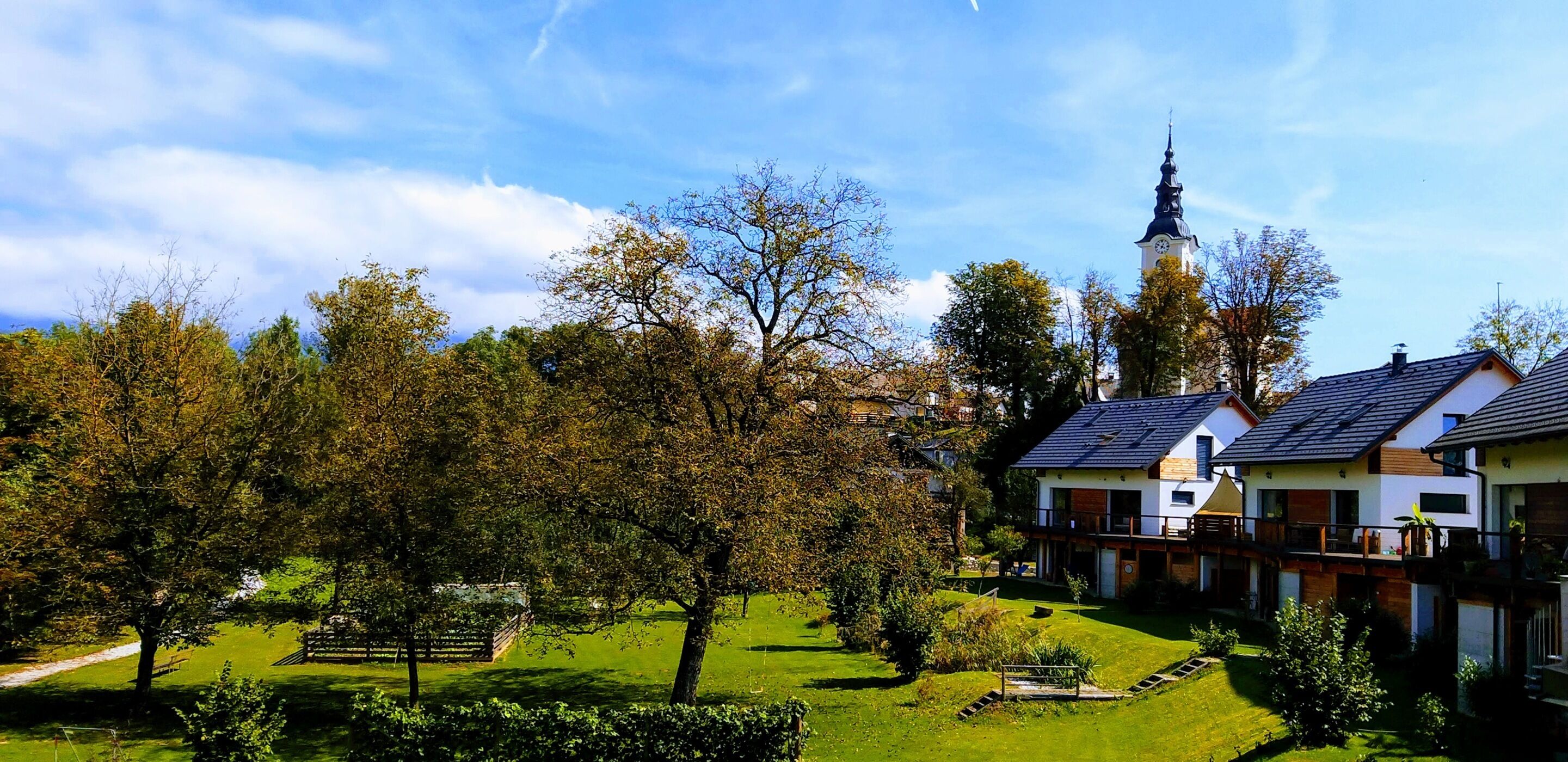 Un quartier résidentiel avec des maisons modernes, un clocher d’église et une pelouse bien entretenue.
