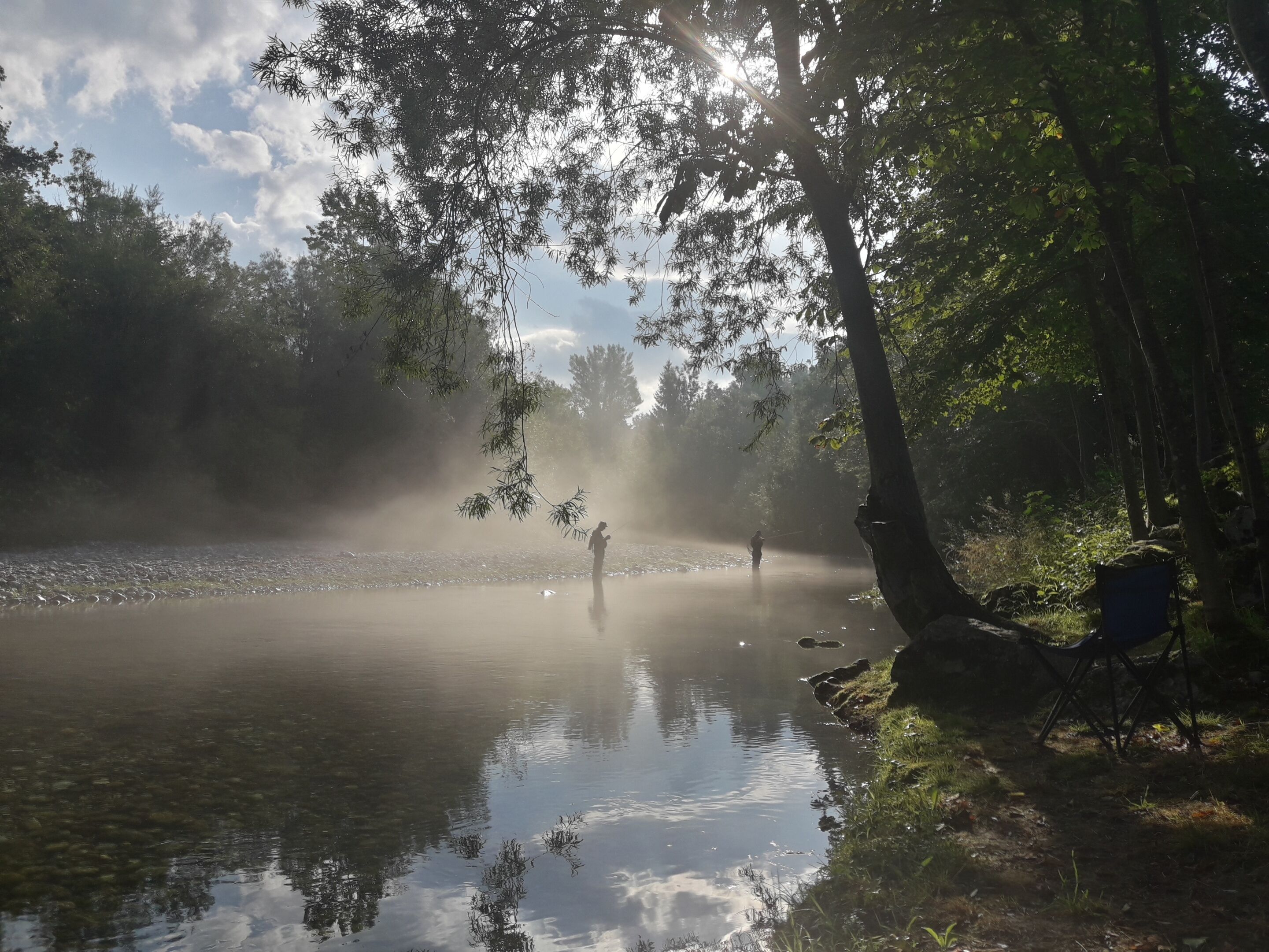 A serene lake surrounded by trees with sunlight filtering through the canopy.