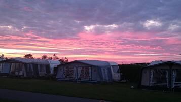 A row of caravans with a sunset sky in the background.