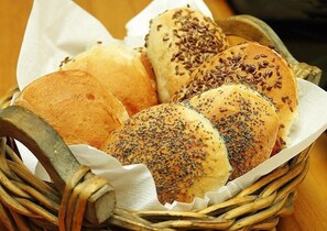 A basket of various types of bread, including rolls and buns with seeds. - Nakskov Fjord Camping (Nakskov)