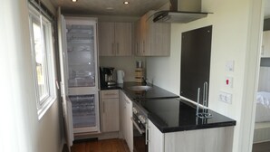 Una cocina compacta con encimera negra, armarios de madera y horno integrado.