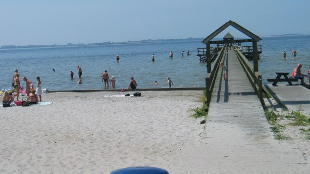 Una playa con un muelle de madera que conduce a una estación de salvavidas.