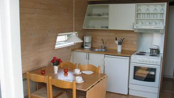 Eine kleine Küche mit Holzausstattung, Spüle, Herd und einem Essbereich mit Stühlen und Tisch.