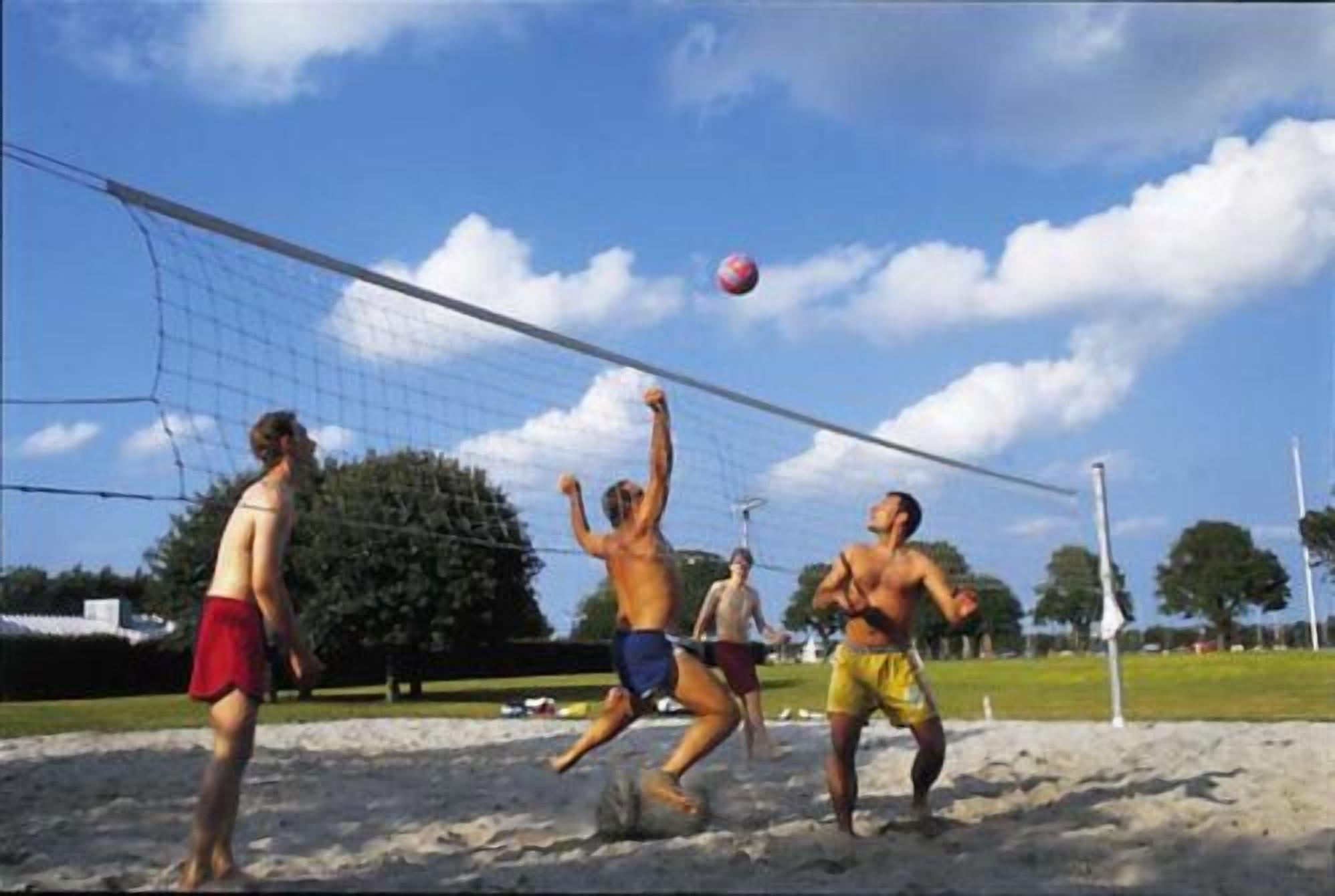Volleyballkamp på en sandbane under en klar himmel.