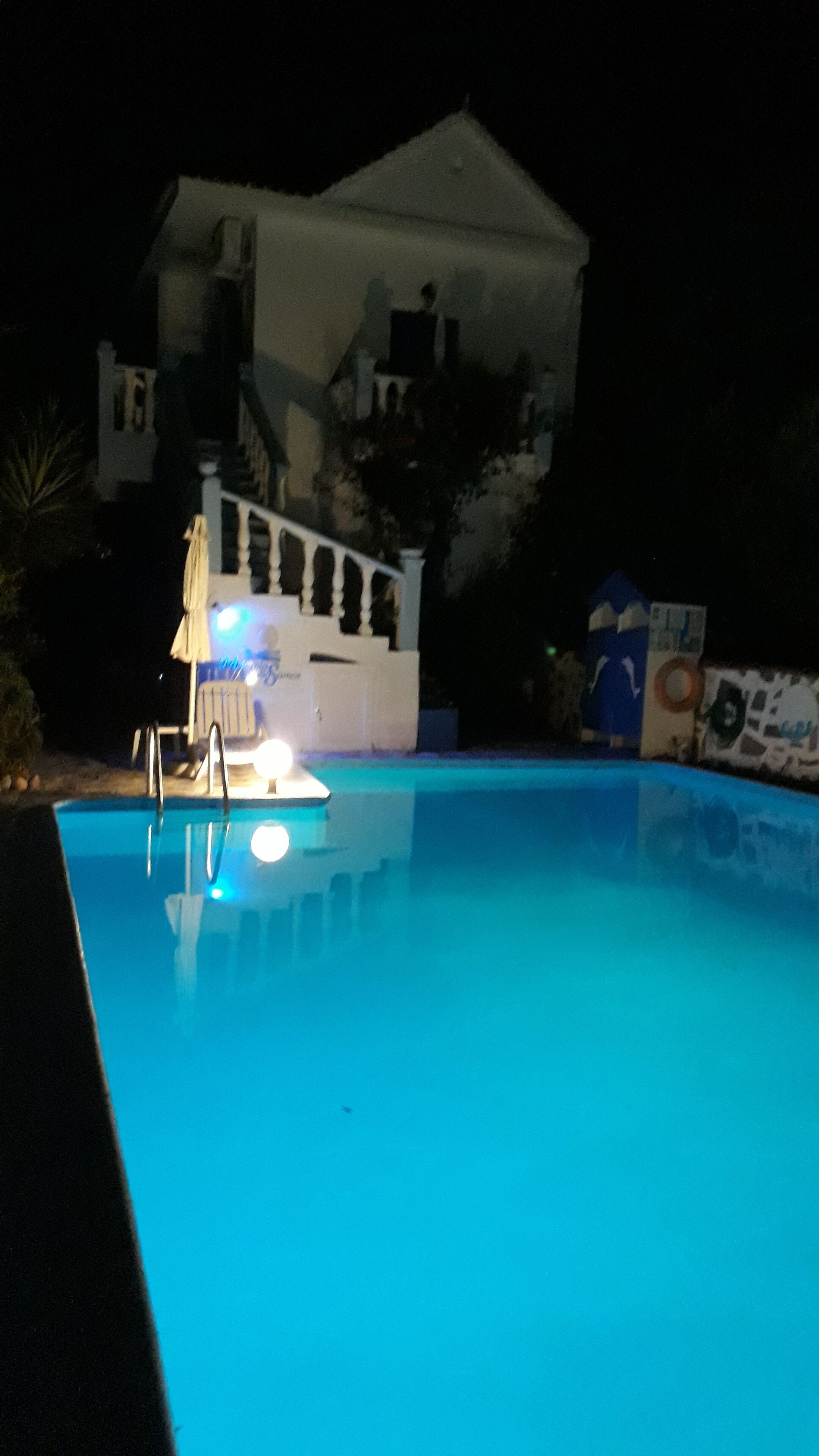 A swimming pool with a lifeguard stand and a white building in the background.