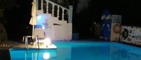 A swimming pool with a lifeguard stand and a white building in the background.
