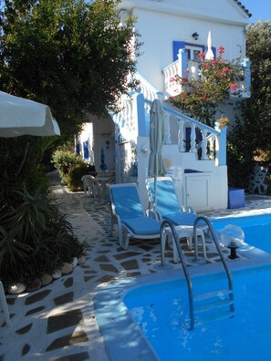Un espace piscine avec des chaises longues et une statue.