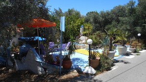 A garden area with potted plants, outdoor seating, and a small pool. - Meltemia Studios Samos (Samos)