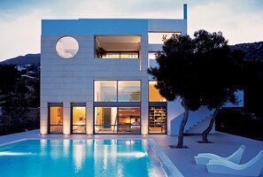 A modern two-story house with a swimming pool, large windows, and a staircase leading to the upper floor. - Minimal Blue Villa (Markopoulo Mesogaias)