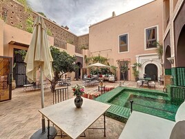 Un patio con piscina, mobiliario exterior y una mesa con un florero.