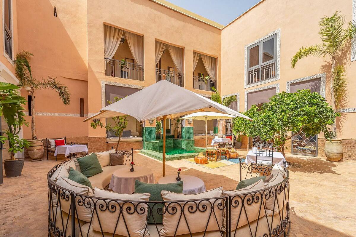 A courtyard with a round seating area, a pool, and a covered seating area.