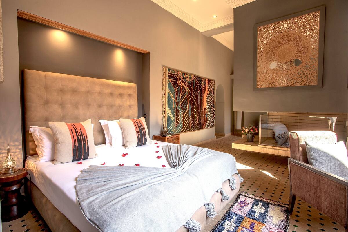 A modern bedroom with a large bed, a nightstand, a bedside table, and a decorative wall piece.
